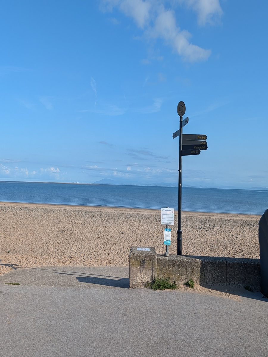 Signpost on Fleetwood Promenade pointing towards Marine Hall, the Fleetwood Promenade parkrun start point, with the beach and sea behind