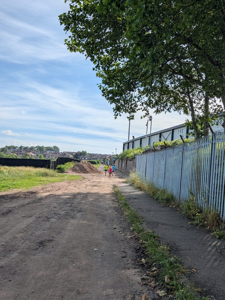 The gravel path heading away from the start at Vale Park parkrun with runners in the distance