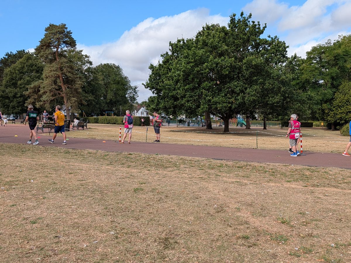 Open grassland and finish funnel area at West Park, Wolverhampton, with parkrun volunteers and the playground in the background